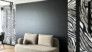 Un salon moderne avec un canapé, une petite table ronde et un mur orné d’un motif zébré.