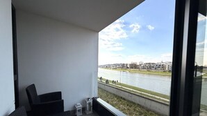 Un balcon donnant sur une rivière et les bâtiments situés de l’autre côté.
