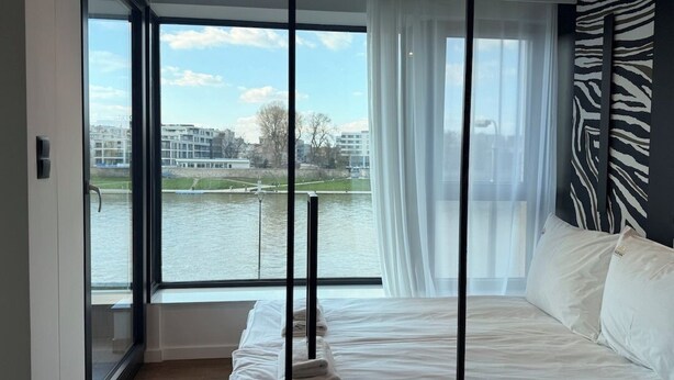Une chambre avec une grande fenêtre, un lit et un mur orné d’un motif zébré.