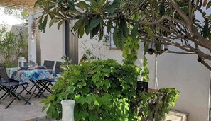 Een buitenmeedeel met een tafel voor twee personen, omringd door groen en een pergola.