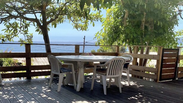 Een houten terras met een tafel en stoelen, met uitzicht op een waterpartij.