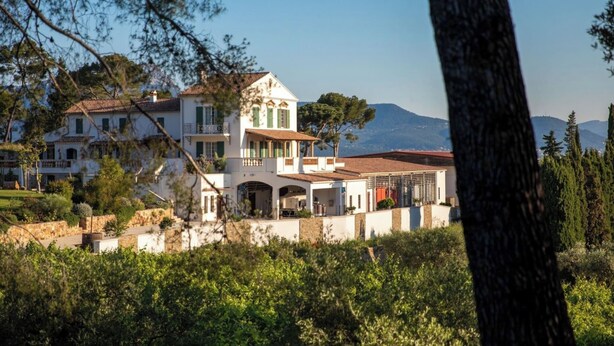 A large, white villa with multiple balconies and a spacious patio area, surrounded by lush greenery and mountains in the background. - Birds II - Domaine de la Navicelle (Le Pradet)