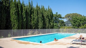 A rectangular swimming pool with a white fence, surrounded by tall trees and a clear sky. - Birds II - Domaine de la Navicelle (Le Pradet)
