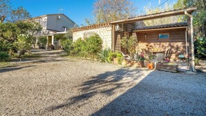 A rustic property with a gravel driveway, a wooden cabin with a porch, and a stone building in the background. - Birds II - Domaine de la Navicelle (Le Pradet)