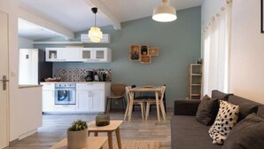 A modern living room with a sofa, coffee table, and a dining area with a table and chairs. - Pinot - Domaine de la Navicelle (Le Pradet)
