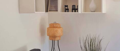A modern living room with a grey sofa, a floor lamp, a potted plant, and a white coffee table.