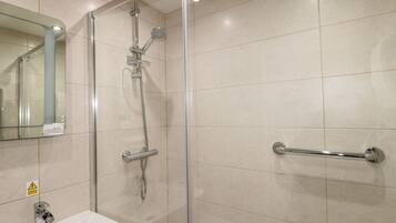A modern bathroom with a glass shower enclosure, a sink with a mirror, and a grab bar for safety.