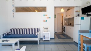 Un espacio habitable compacto con sofá, una mesita, kitchenette y ventilador de techo.