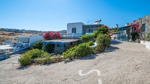 Un edificio costiero con facciata in pietra, tetto blu e un giardino con fiori rosa.