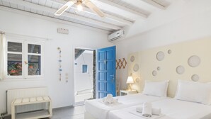Habitación de hotel con dos camas, un radiador blanco, un banco y una puerta azul.