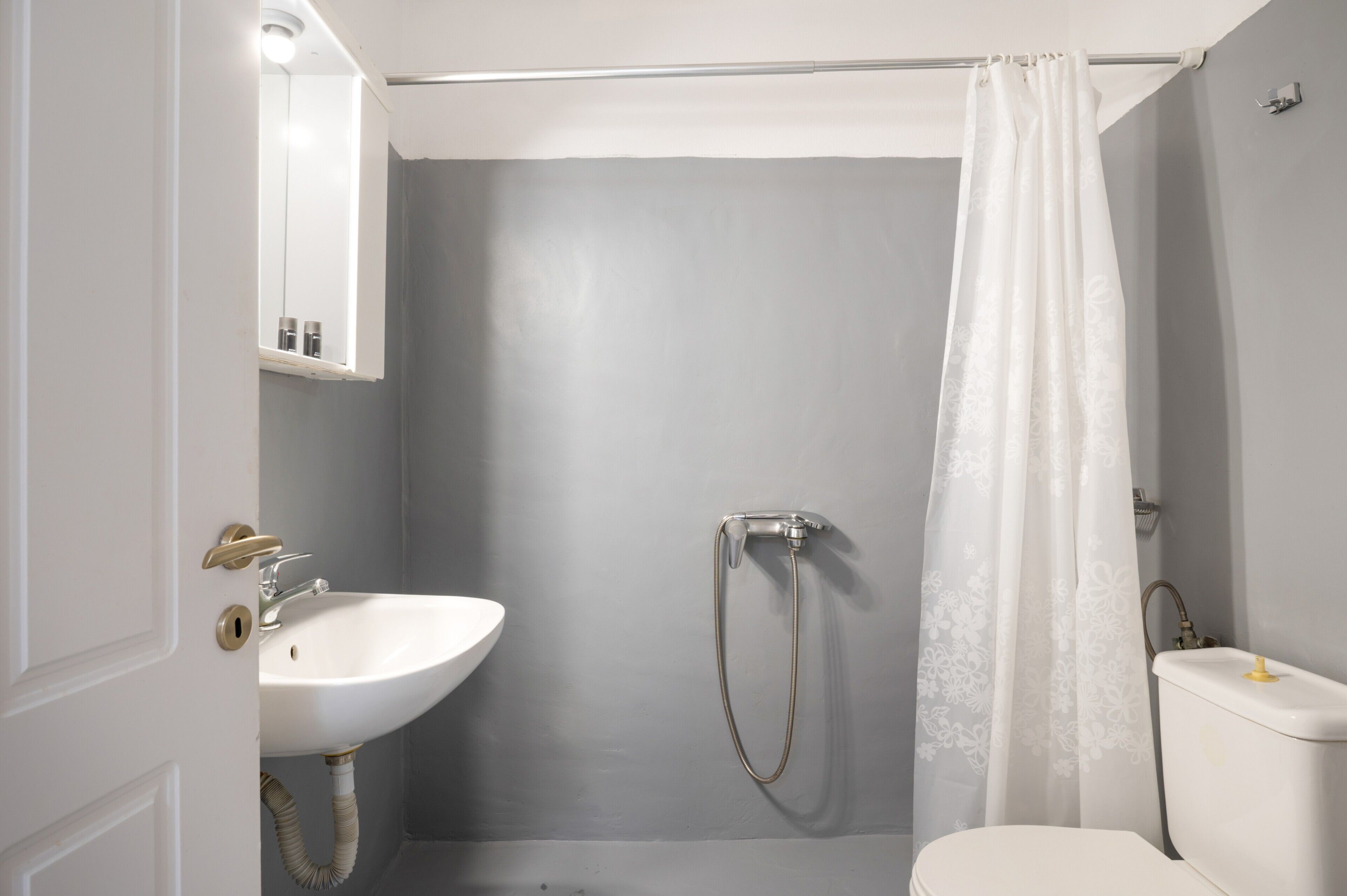 A bathroom with a white sink, a shower with a curtain, and a toilet.