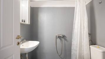 A bathroom with a white sink, a shower with a curtain, and a toilet.