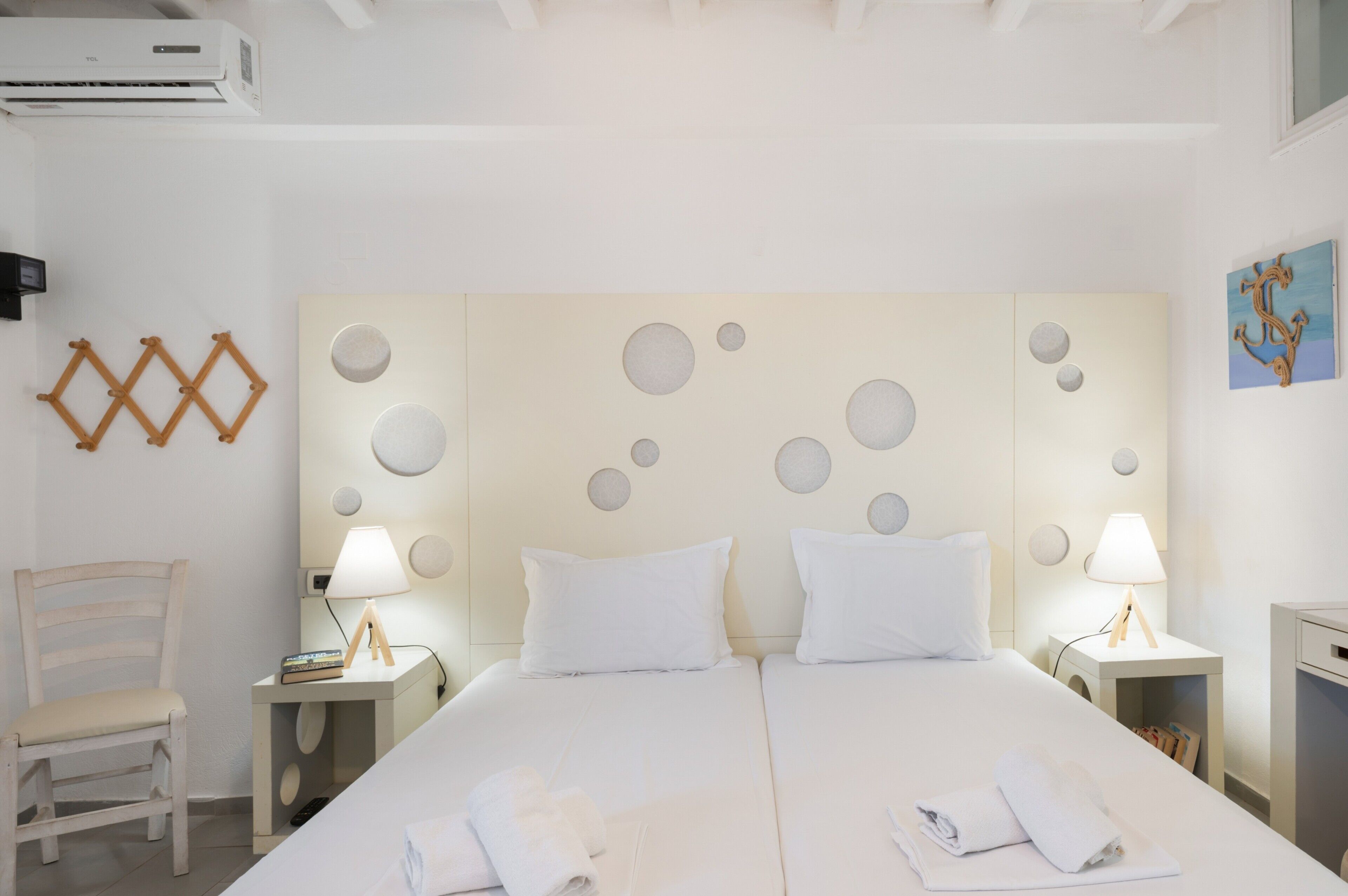A hotel room with a large bed, two bedside tables with lamps, a chair, and a wall-mounted air conditioner.