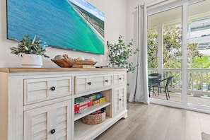 A room with a large window offering a view of the ocean and a balcony with outdoor furniture. - Azure on 30A 1-205- A Wave From it All (Santa Rosa Beach)