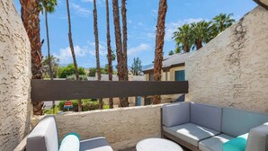 A patio with a gray sofa, a round table, and a wooden pergola. - @ Marbella Lane - Gem w/ Outdoor Fun Pool & Trails (Palm Springs)