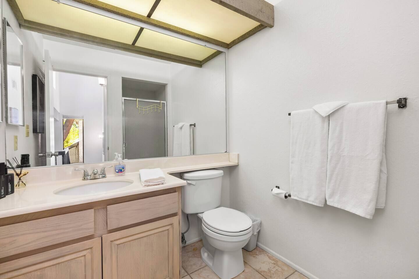 Une salle de bain moderne avec un grand miroir, un lavabo, des toilettes et un espace douche.