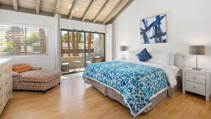 A bedroom with a large bed, a nightstand, a chair, and a view of the outdoors through a sliding door. - @ Marbella Lane - Gem w/ Outdoor Fun Pool & Trails (Palm Springs)
