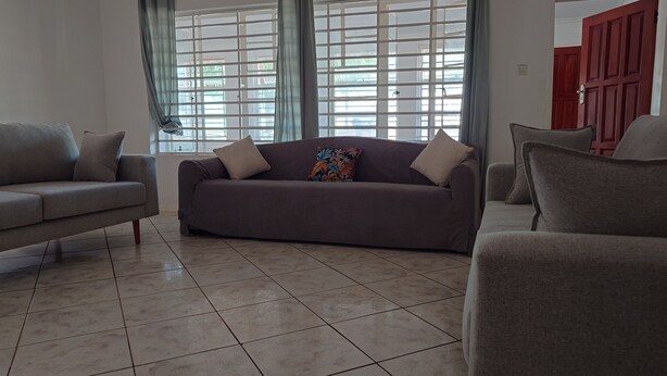 Un salon comprenant un canapé, deux fauteuils et un coussin décoratif à motifs.