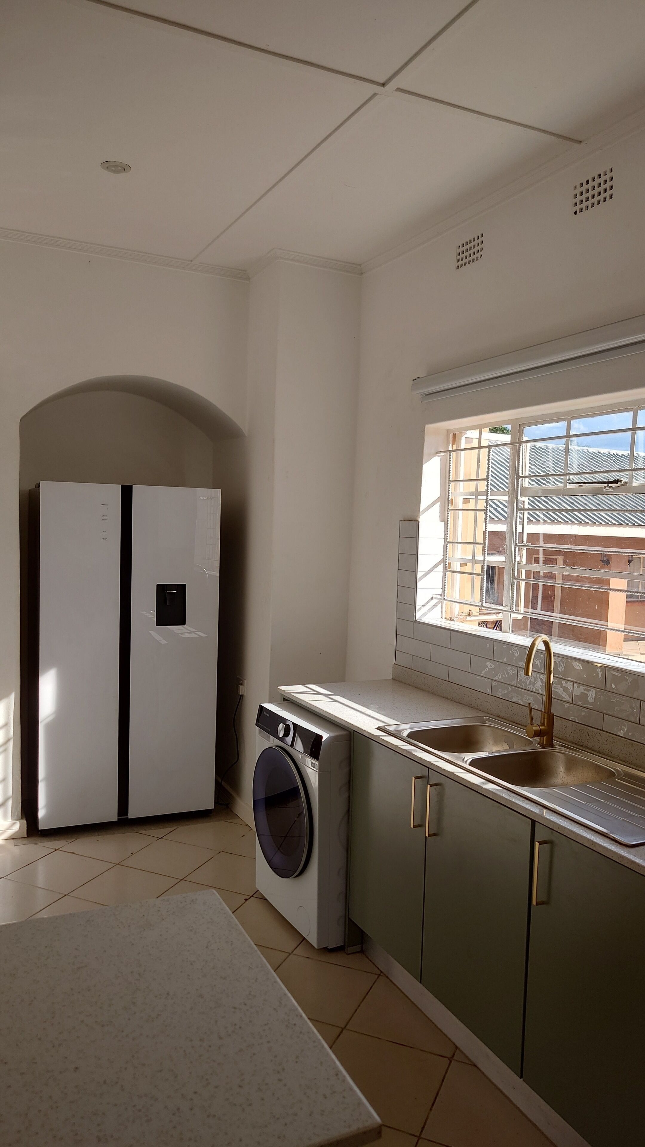 Una cucina compatta con lavatrice integrata, un lavello e una finestra vista edifici.