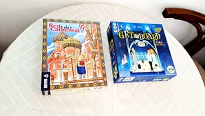 Deux jeux de société, « La Cathédrale rouge » et « À bord de Paris », sont posés sur une table blanche.