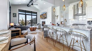 A modern kitchen with a large island, bar stools, and a fireplace. - Canyons Village Retreat with On-Demand Shuttle, Hot Tub by Park City Lodging (Park City)
