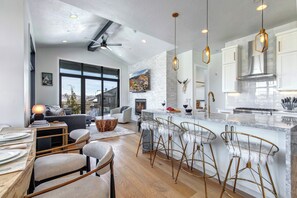 Eine moderne Küche mit einer großen Kochinsel, Barhocker und einem Kamin.