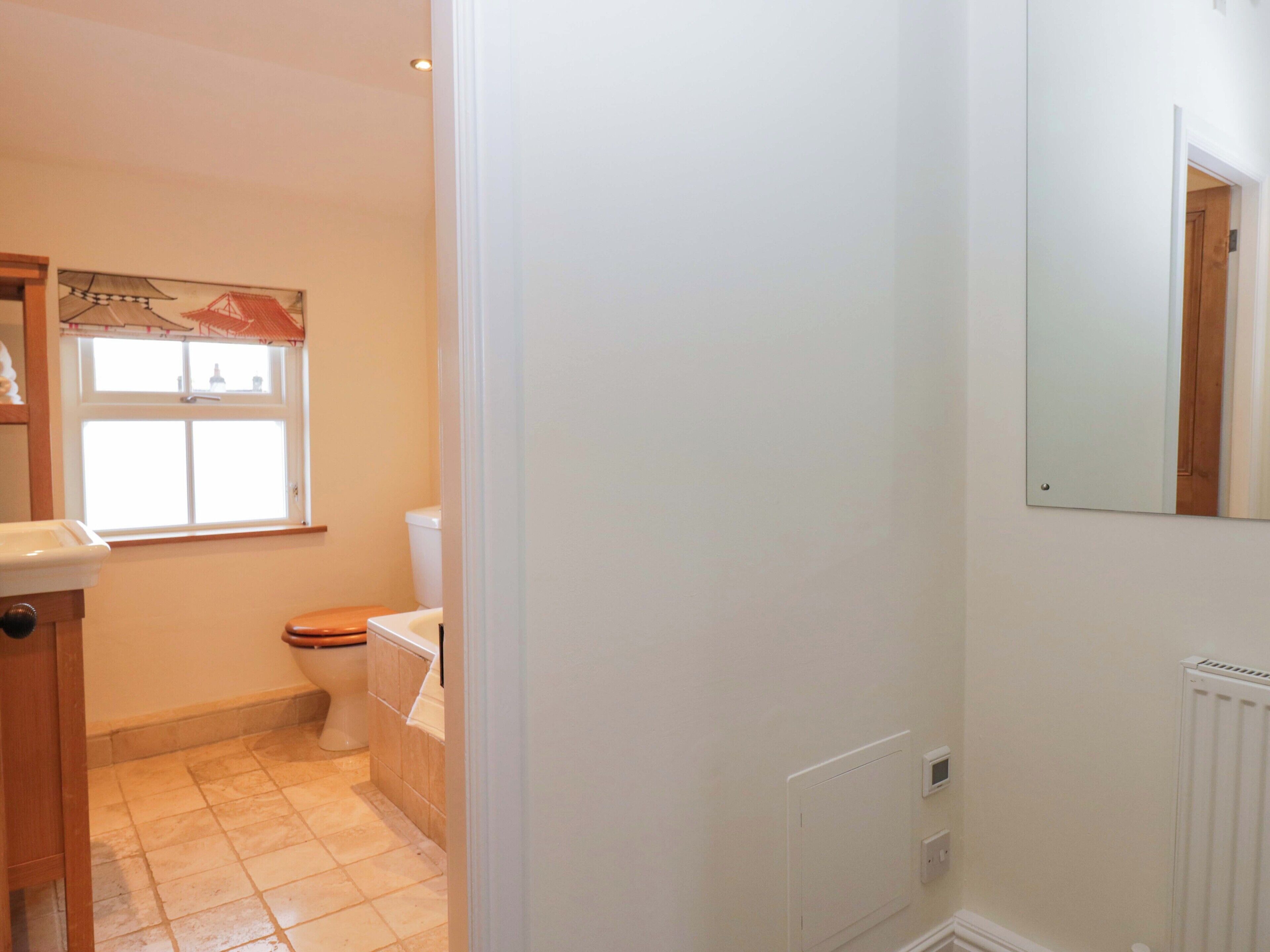 Ein kleines, sauberes Badezimmer mit Toilette, Waschbecken und Fenster.