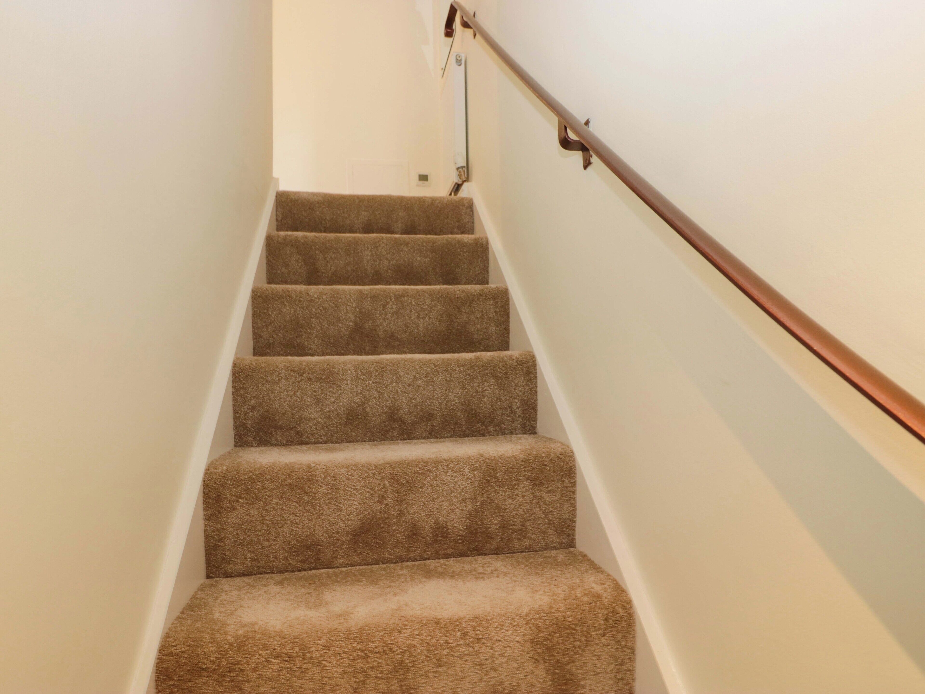 Una escalera alfombrada con barandilla de madera.