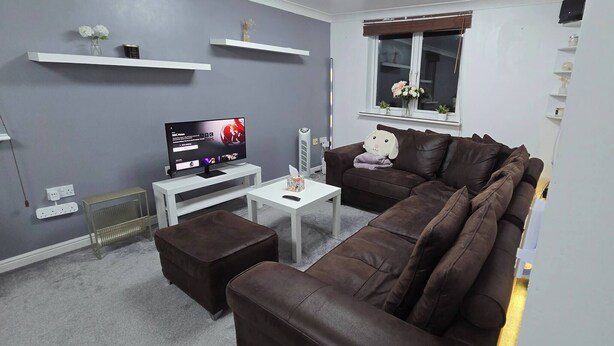 Ein modernes Wohnzimmer mit einem braunen Ledersofa, einem weißen Couchtisch und einem Flachbildfernseher auf einem weißen Schrank.