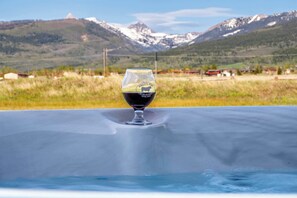 Un verre de vin rouge sur une table, avec un paysage montagneux en arrière-plan.