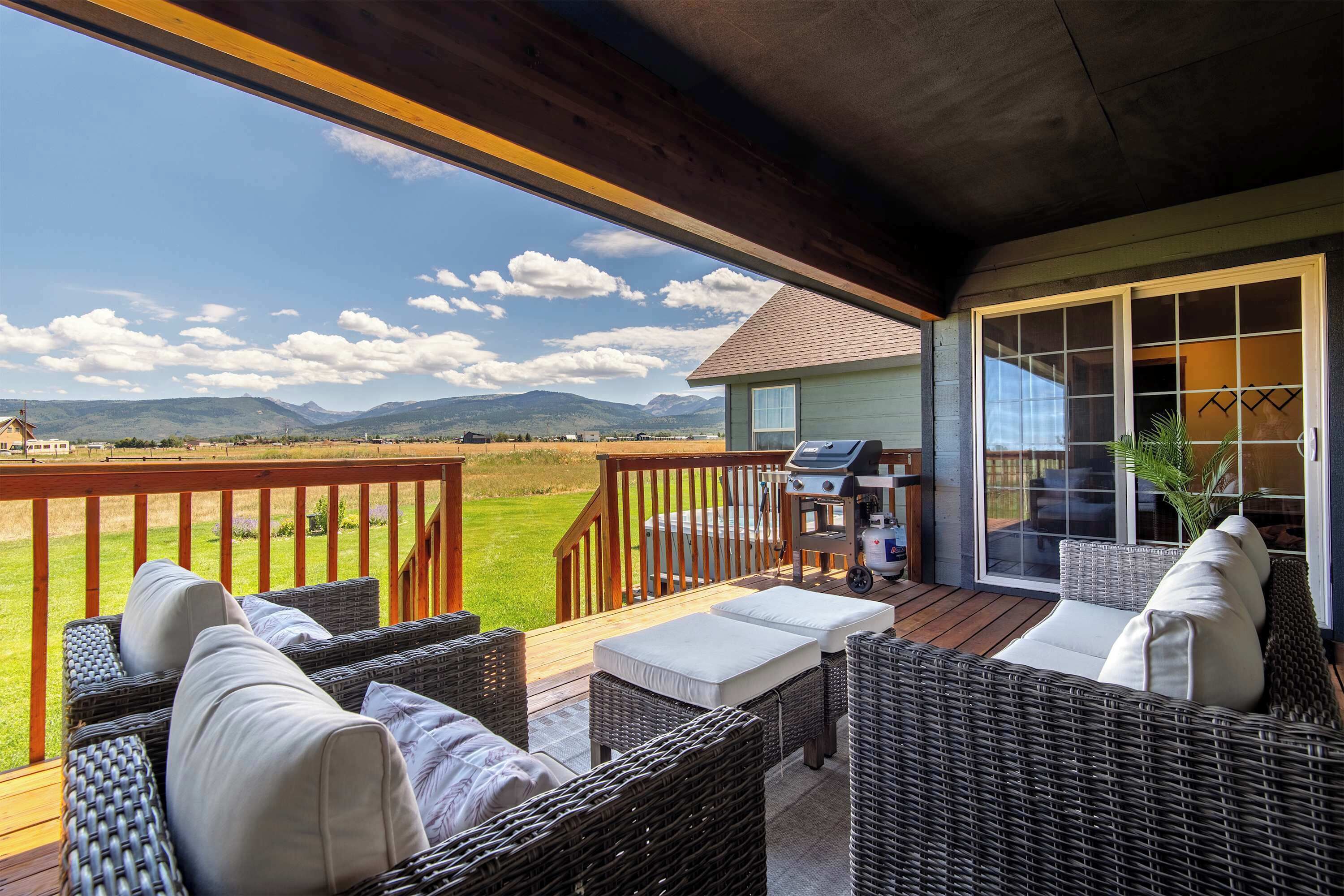 A covered outdoor seating area with wicker furniture and a view of the landscape.