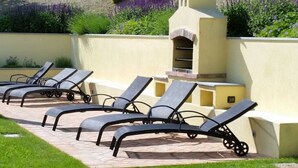 A patio with lounge chairs and a built-in barbecue grill. - Country House Amista by Italita (Nizza Monferrato AT)