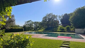 A swimming pool with a brick pathway leading to it, surrounded by well-maintained grass and trees. - Country House Amista by Italita (Nizza Monferrato AT)