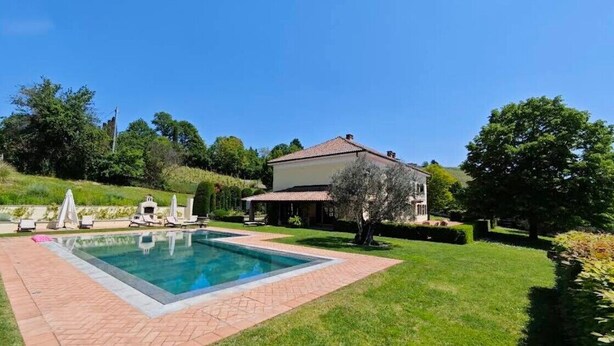 A swimming pool with lounge chairs, a house, and a well-maintained lawn. - Country House Amista by Italita (Nizza Monferrato AT)