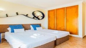 Hotellihuone, jossa on sänky, vaatekaappi ja peili seinällä.