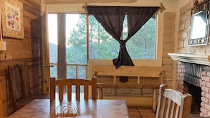 En matplats med träinredning, en tegelkamin, en bänk och ett fönster med gardin.