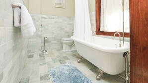 A bathroom with a bathtub, toilet, and a blue rug. - Charming Conshohocken B+B Near Philly (Conshohocken)