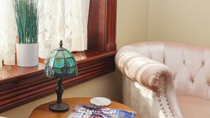 A cozy room with a round wooden table, a green glass lamp, a magazine, and a plush armchair. - Charming Conshohocken B+B Near Philly (Conshohocken)