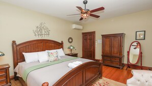 A bedroom with a wooden bed, a ceiling fan, a wardrobe, a mirror, and a small table with a lamp. - Charming Conshohocken B+B Near Philly (Conshohocken)