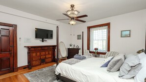 A bedroom with a bed, a television, a ceiling fan, a fireplace, and a window with curtains. - Charming Conshohocken B+B Near Philly (Conshohocken)