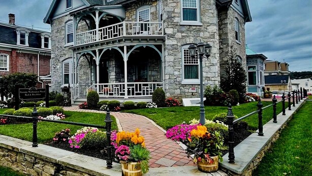 A large stone house with a prominent tower, multiple balconies, and a well-maintained garden with colorful flowers. - Boutique Conshohocken (near Philadelphia) King & Queen Suite - Breakfast Included (Conshohocken)