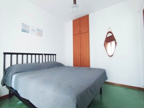 A bedroom with a bed, a wardrobe, and a wall-mounted mirror. - Bright Holiday Home With Balcony (Jesolo)