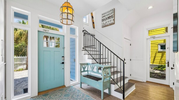 Un intérieur de maison avec un escalier, une porte bleue et une porte jaune.