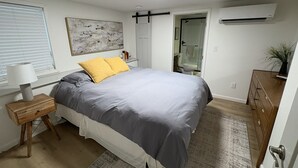 Une chambre moderne avec un lit, une table de chevet et une fenêtre avec des stores.