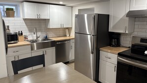 Une cuisine moderne avec des meubles blancs, des appareils en acier inoxydable et un plan de travail en bois.