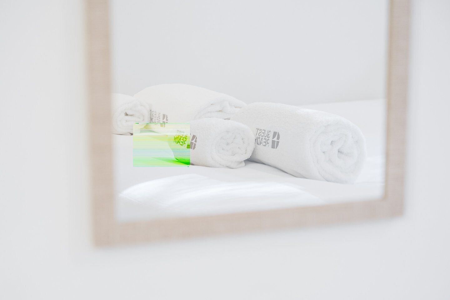 A neatly arranged set of white towels with a visible logo on a white surface, likely in a hotel room.