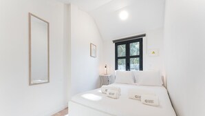 Une chambre à coucher avec un lit, une table de chevet, un miroir et une fenêtre.