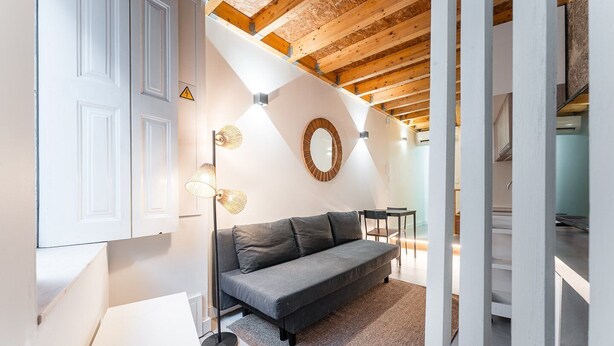 Un intérieur moderne avec un canapé gris, une lampe sur pied et un plafond en bois.