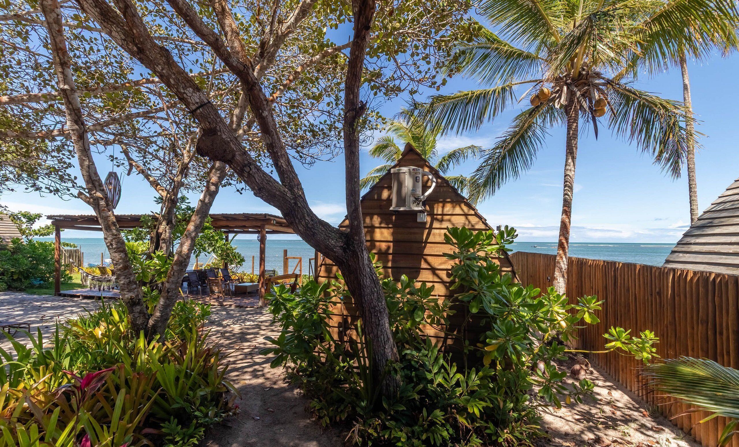 A tropical outdoor area with a wooden structure, palm trees, and a view of the ocean.
