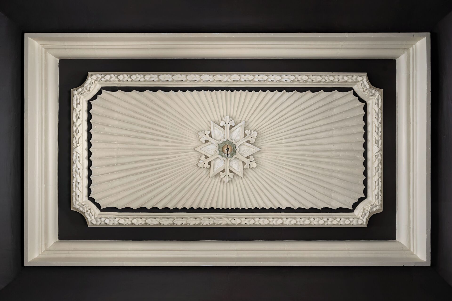 En indramet arkitektonisk detalje med et centralt dekorativt element og et symmetrisk design.